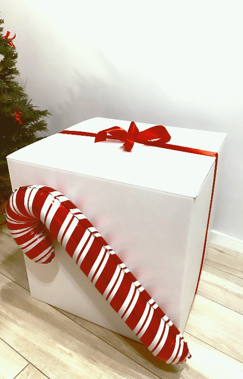 Biały box z czerwoną kokardą udekorowany lizakiem